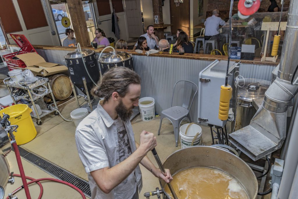 Man stirs craft beer in pot