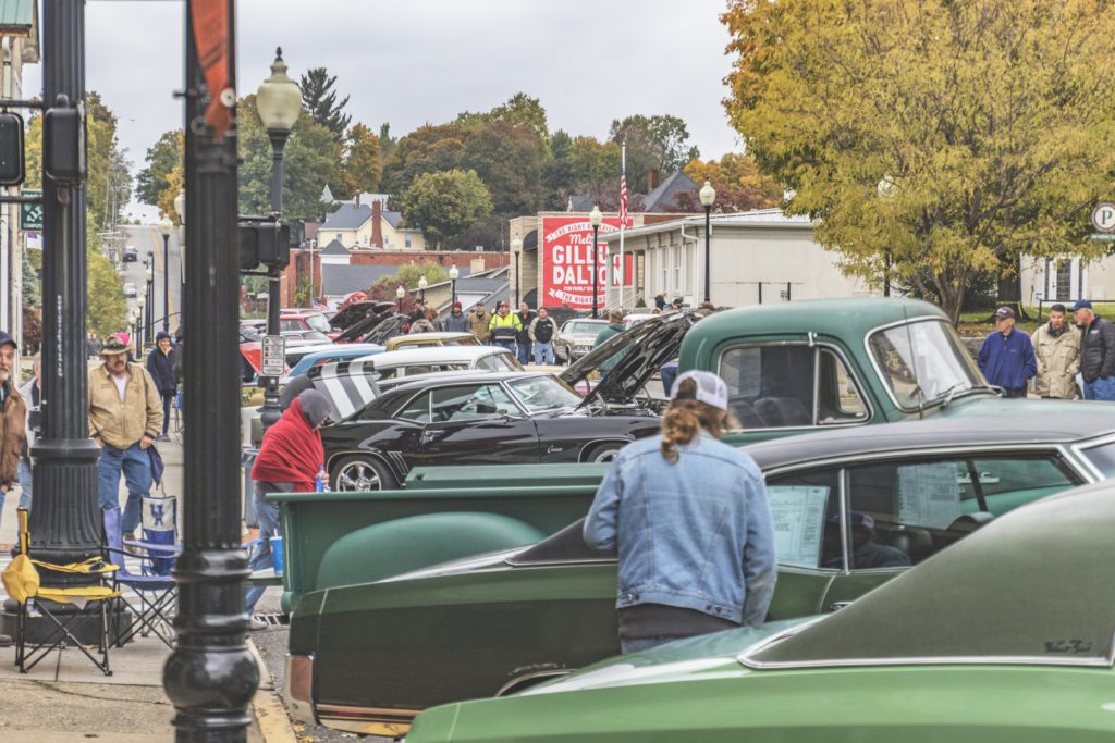 People look at classic cars and trucks on street