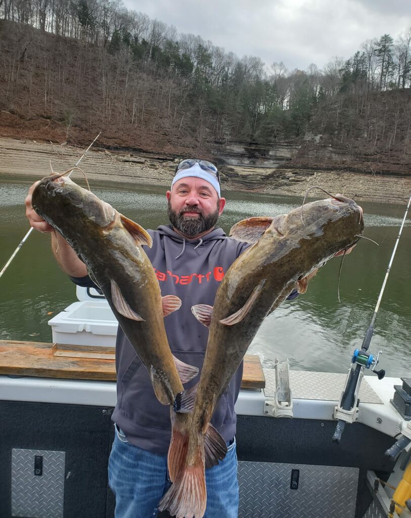 A guy holding two large catfishes that were caught on Lake Cumberland.