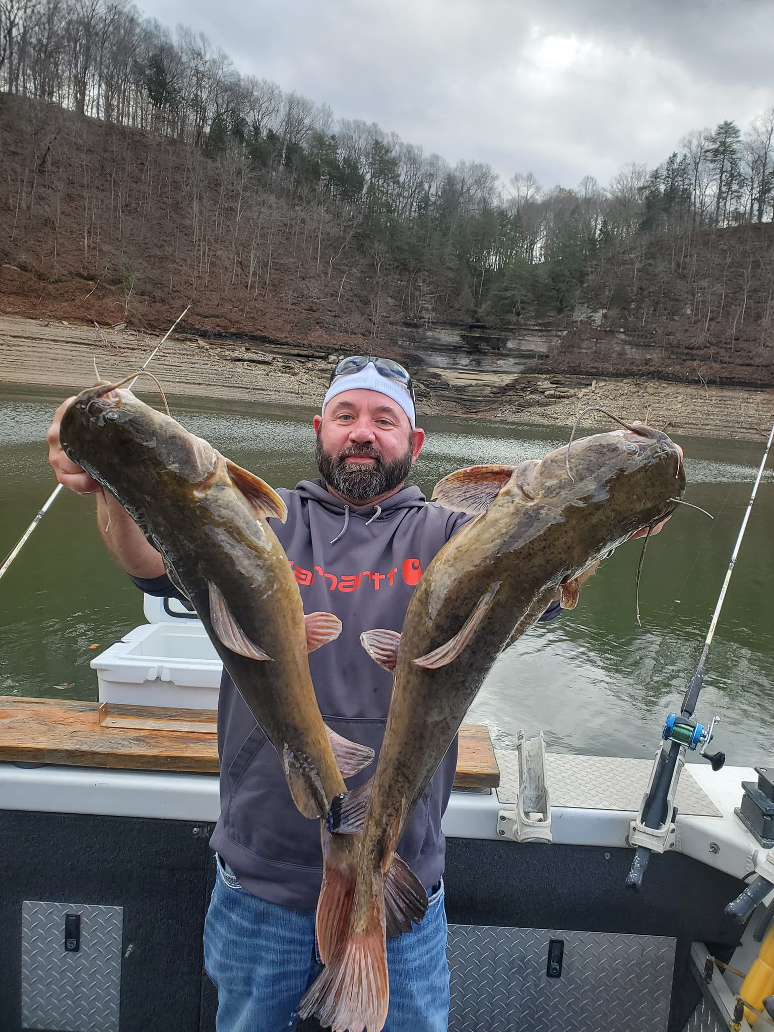 A guy holding two large catfishes that were caught on Lake Cumberland.