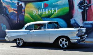 Old show car parked in front of a wall mural with the words I love (heart symbol) Somerset.