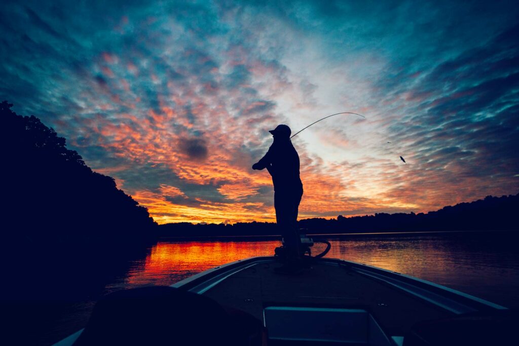 Silhouette of fisherman on a boat at sunset.
