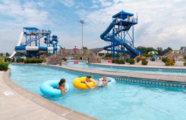 Kids floating down the lazy river flowing pool with large water slides in the background.