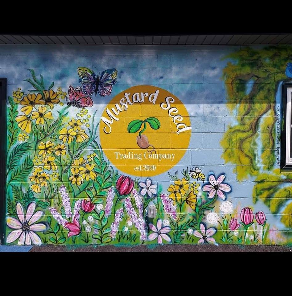 Colorful flower mural with the Mustard Seed Trading Co. logo on the building